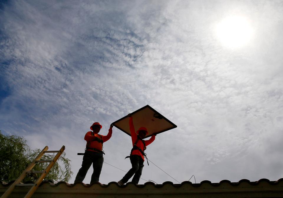 In this July 28, 2015 file photo, electricians install solar panels on a roof for Arizona Public Service company in Goodyear, Ariz. Corporation Commissioner Andy Tobin wants to see 80 percent of Arizona's energy come from 'clean' resources by 2050.