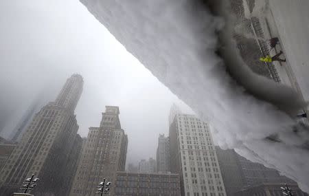 A worker is reflected in the sculpture "Cloud Gate" as he pushes a snow plough to clear a path during blizzard conditions in Chicago, Illinois, February 1, 2015. REUTERS/Jim Young