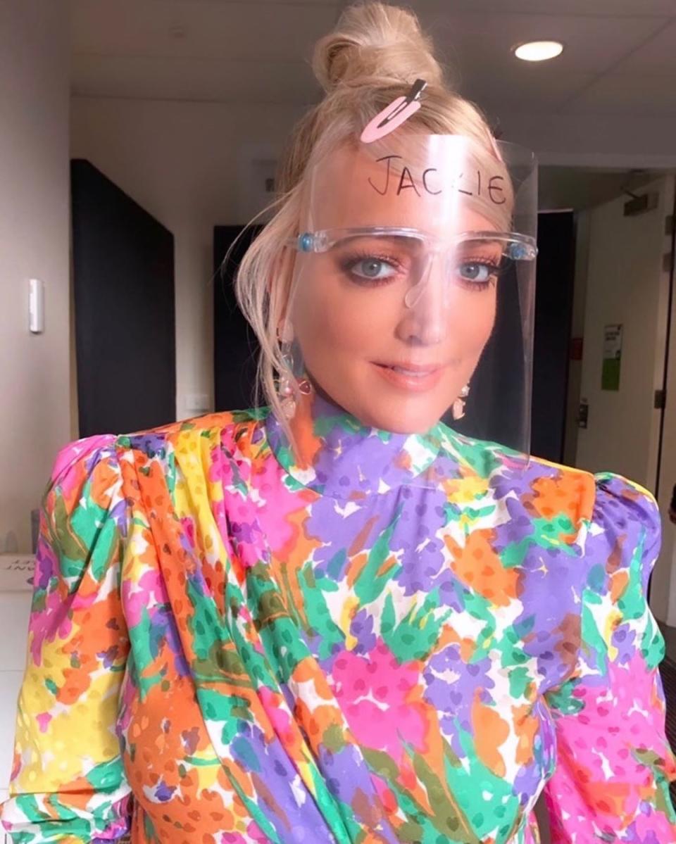 Jackie 'O' Henderson wearing a plastic face shield and a colourful dress backstage on The Masked Singer