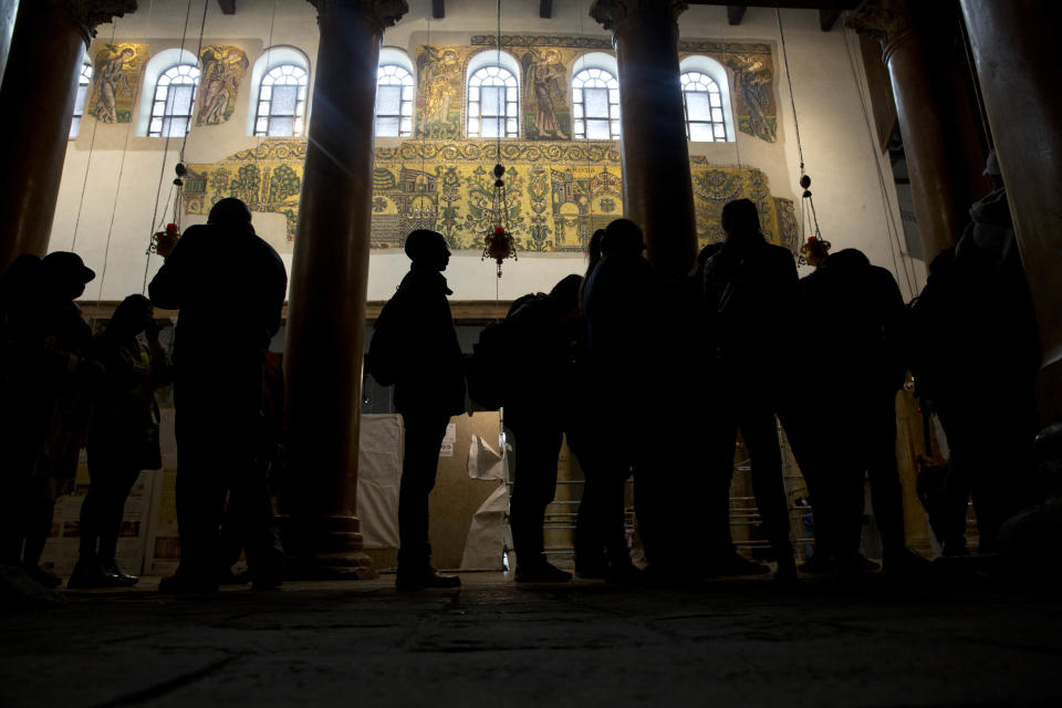 In this Thursday, Dec. 6, 2018 photo, visitors stand bellow a renovated part of a fresco inside the Church of the Nativity, built atop the site where Christians believe Jesus Christ was born, in the West Bank City of Bethlehem. City officials are optimistic that the renovated church will help add to a recent tourism boom and give a boost to the shrinking local Christian population. (AP Photo/Majdi Mohammed)