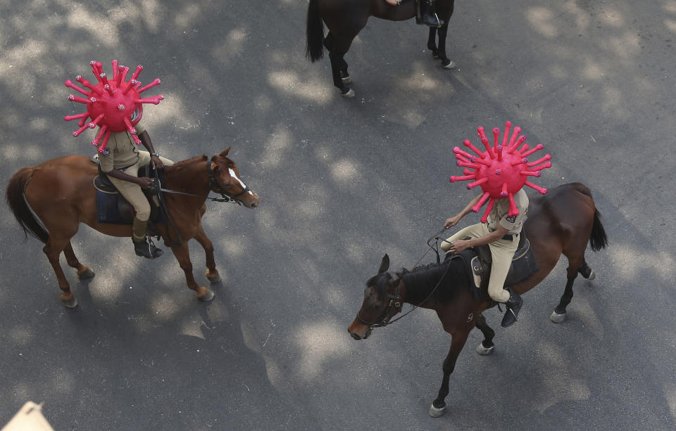 FILE- In this April 2, 2020 file photo, Indian policeman wearing virus themed helmets ride on horses during an awareness rally aimed at preventing the spread of new coronavirus in Hyderabad, India. India, a bustling country of 1.3 billion people, has slowed to an uncharacteristic crawl, transforming ordinary scenes of daily life into a surreal landscape. The country is now under what has been described as the world’s biggest lockdown, aimed at keeping the coronavirus from spreading and overwhelming the country’s enfeebled health care system. (AP Photo/Mahesh Kumar A, File)
