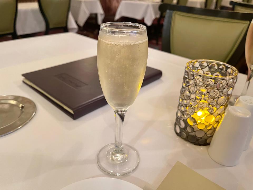 Glass of champagne on tablecloth-covered table.
