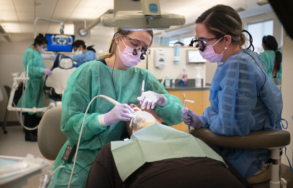 PORTLAND, ME - NOVEMBER 1: Meghan McAlary, left, and Tasha Seavey, dental students at the University of New England, perform a dental cleaning on Jason Weinberg at the school's Oral Health Center in Portland on Friday, November 1, 2019. The university partnered with the Maine Dental Association for the 11th annual Dentists Who Care for ME event, a day in which dentists throughout Maine provide free dental care for people who cannot afford treatment and don't have insurance. UNE's College of Dental Medicine, which started in 2014 and has 256 students enrolled, provided free dental services to 145 patients on Friday. (Staff Photo by Gregory Rec/Portland Press Herald via Getty Images)