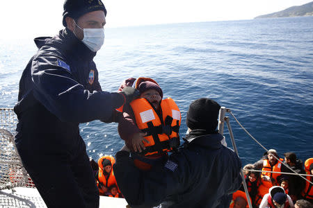 Greek Coast Guard officers move a baby from a dinghy carrying refugees and migrants aboard the Agios Efstratios Coast Guard vessel, during a rescue operation at open sea between the Turkish coast and the Greek island of Lesbos, in this February 8, 2016 file photo. REUTERS/Giorgos Moutafis/Files