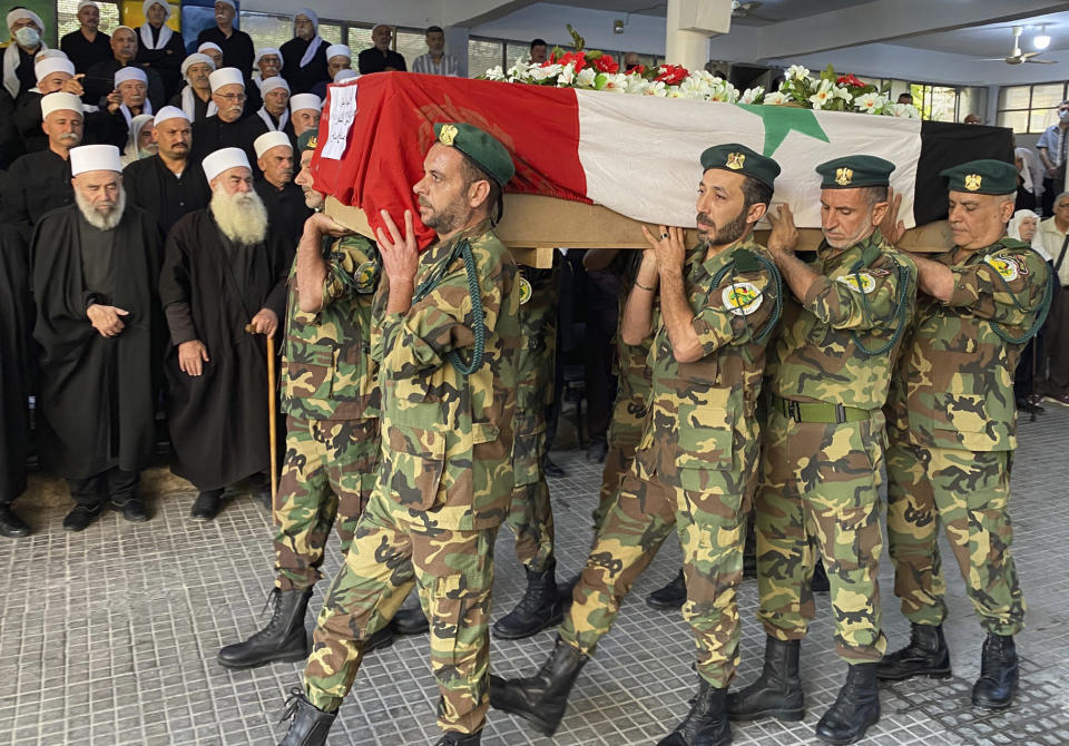 Volunteers from the Baath battalions carry the Syrian flag-wrapped coffin of former Syrian Druze lawmaker Midhat Saleh, allegedly shot by Israeli sniper fire, in Ein el-Tineh, a village along the Israeli frontier in the Golan Heights, during his funeral procession in Jaramana, southeast of Damascus, Syria, Monday, Oct. 18, 2021. Saleh was born in Majdal Shams, in the Israeli-controlled side of the Golan, and was jailed several times by Israel, most recently for 12 years until 1997. (AP Photo)