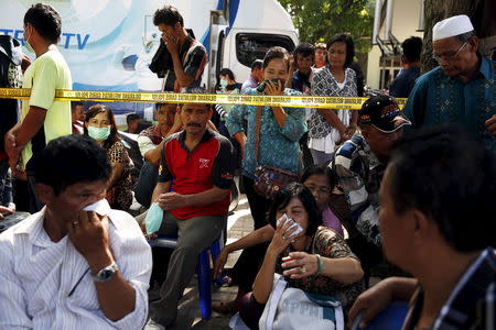 Relatives of the victims of an Indonesian military C-130 Hercules transport plane that crashed into a residential area cover their noses as they sit near the morgue at Adam Malik hospital in Medan, Indonesia North Sumatra province July 2, 2015. REUTERS/Beawiharta