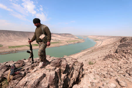 A Syrian Democratic Forces(SDF) fighter poses for a picture near Euphrates River, north of Raqqa city, Syria. REUTERS/Rodi Said