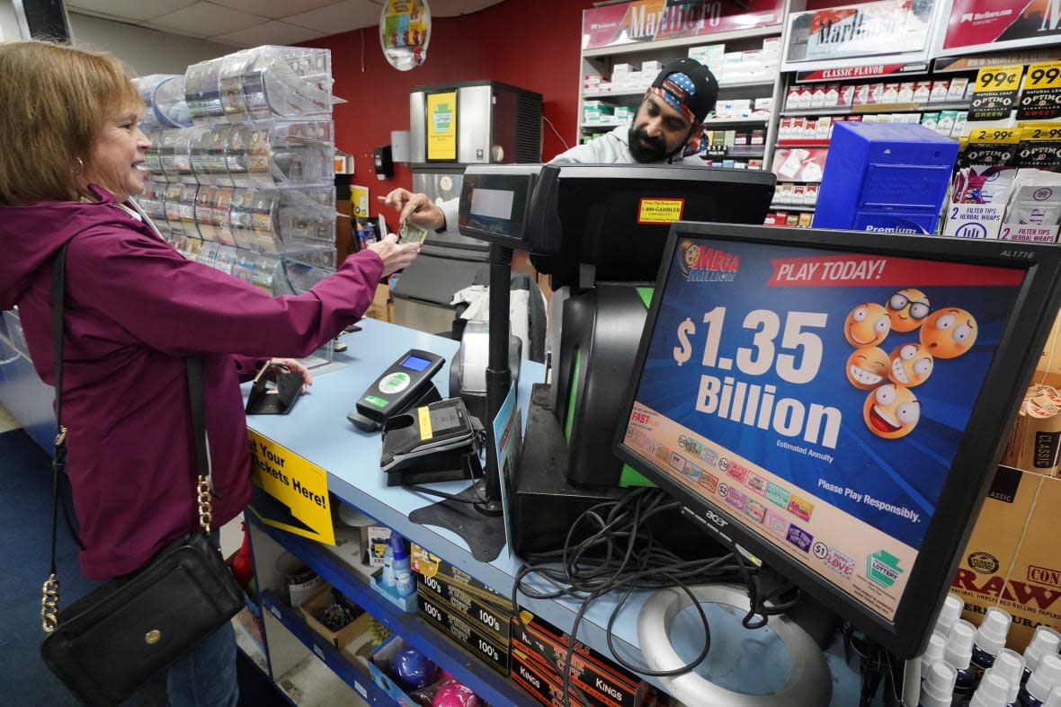 FILE – A Mega Millions sign displays the estimated jackpot of $1.35 billion as a customer purchases a Mega Millions ticket at the Cranberry Super Mini Mart in Cranberry, Pa., Thursday, Jan. 12, 2023. Someone matched all six numbers Friday and won the jackpot, overcoming steep odds that led to three months of drawings without a winner.( AP Photo/Gene J. Puskar, File)