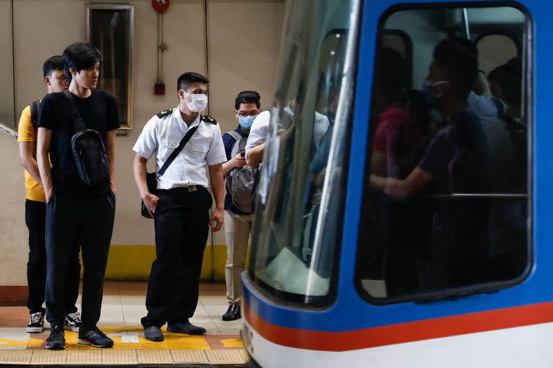 Passengers wearing protective masks wait for a train to arrive at the station in Manila