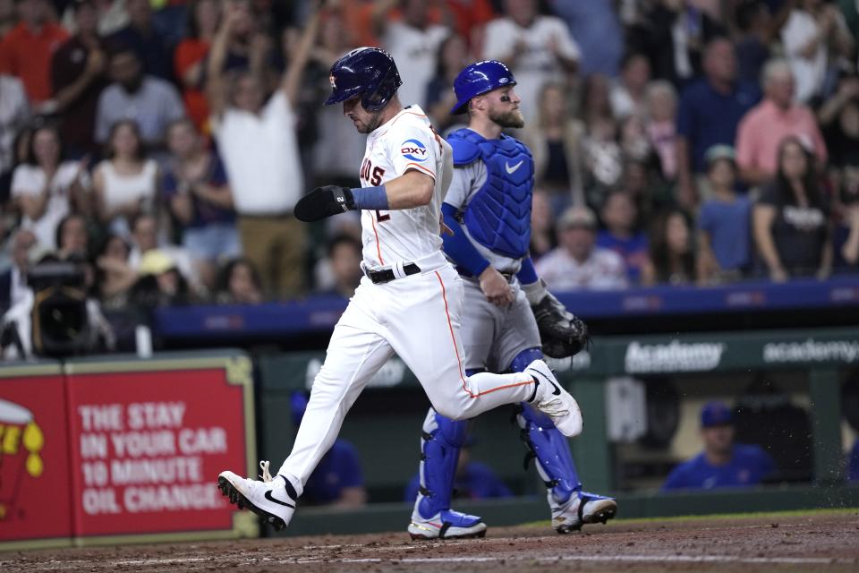 Houston Astros' Alex Bregman (2) scores as Chicago Cubs catcher Tucker Barnhart stands behind home plate during the fourth inning of a baseball game Tuesday, May 16, 2023, in Houston. (AP Photo/David J. Phillip)