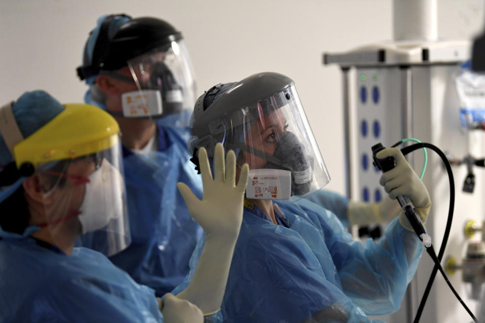 FILE - In this May 5, 2020 file photo members of the medical staff care for a patient with coronavirus as they are treated in the intensive care unit at the Royal Papworth Hospital in Cambridge, England. More than 100,000 people have died in the United Kingdom after contracting the coronavirus. That's according to government figures released Tuesday Jan. 26, 2021. Britain is the fifth country in the world to pass that mark, after the United States, Brazil, India and Mexico, and by far the smallest. The U.S. has recorded more than 400,000 COVID-19 deaths, the world's highest total, but its population of about 330 million is about five times Britain's. (Neil Hall/Pool via AP, File)