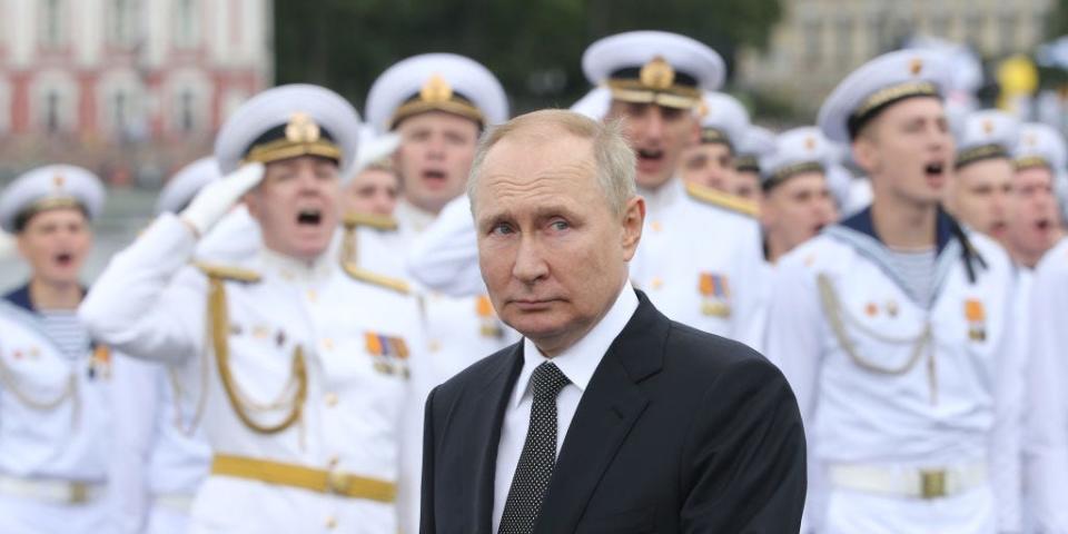 Vladimir Putin with Navy officers in white uniforms behind him.