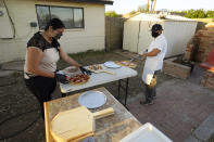 Ruby Salgado, left, and her husband chef Jose Hernandez prepare pizzas in the backyard of their home in Scottsdale, Ariz. on April 3, 2021. Beaten down by the pandemic, some laid-off or idle restaurant workers have pivoted to dishing out food from home. (AP Photo/Ross D. Franklin)