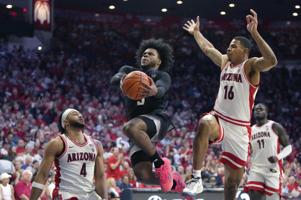 Washington guard Sahvir Wheeler (5) drives between Arizona guard Kylan Boswell (4) and forward Keshad Johnson (16) during the first half of an NCAA college basketball game, Saturday, Feb. 24, 2024, in Tucson, Ariz. (AP Photo/Rick Scuteri)