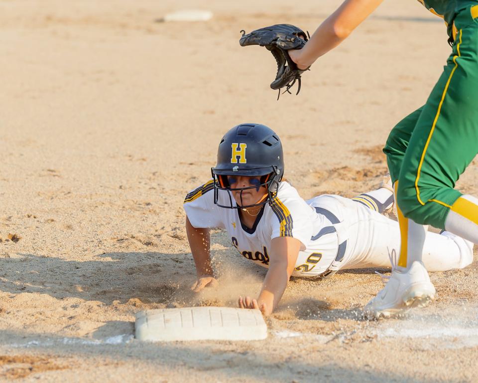 Hartland's Reese Dunny dives back to first base ahead of a pickoff throw during a 3-0 victory over Grosse Pointe North in a state quarterfinal Wednesday, June 14, 2023 at Wayne State University.