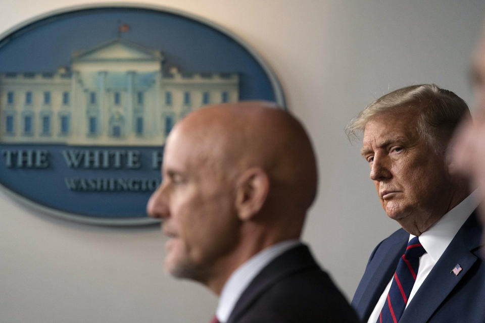 FILE - In this Aug. 23, 2020, file photo President Donald Trump, listens as Food and Drug Administration Commissioner Dr. Stephen Hahn, left, speaks during a media briefing in the James Brady Briefing Room of the White House in Washington. Hahn, the head of the agency responsible for approving any COVID-19 vaccine, was summoned to the White House Tuesday, Dec. 1, as an increasingly frustrated President Donald Trump complained that approval hasn't moved faster. (AP Photo/Alex Brandon, File)