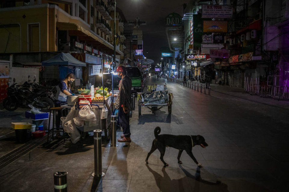 An alone street vender cooks a meal for a customer at Khao San road, a popular hangout with bars and entertainment for Thais and tourists in Bangkok, Thailand, Monday, Jan. 4, 2021. For much of 2020, Thailand had the coronavirus under control. After a strict nationwide lockdown in April and May, the number of new local infections dropped to zero, where they remained for the next six months. However, a new outbreak discovered in mid-December threatens to put Thailand back where it was in the toughest days of early 2020. (AP Photo/Gemunu Amarasinghe)