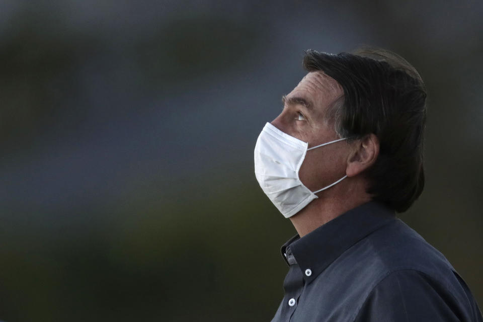 Brazil's President Jair Bolsonaro, who tested positive for COVID-19, wearing a protective face mask attends a Brazilian flag retreat ceremony outside the Alvorada Palace, in Brasilia, Brazil, Monday, July 20, 2020. (AP Photo/Eraldo Peres)