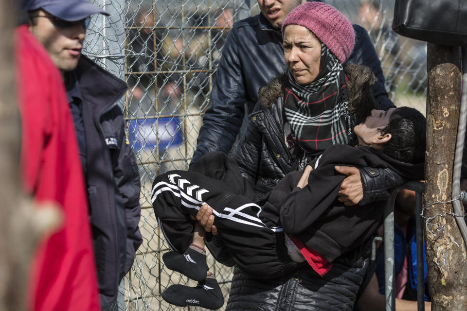 A woman holding a disabled child waits to cross the Greece-Macedonia border on March 3, 2016. Authorities are only allowing a handful of people to cross each day.