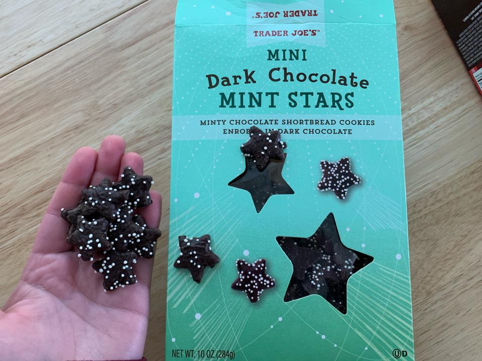 hold holding trader joes dark chocolate mint stars beside blue box of them