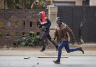 Protesters run for cover as they clash with police outside the Eldorado Park police station in Johannesburg, South Africa, Thursday, Aug. 27, 2020. Residents from the township, south of Johannesburg are demanding justice for a teenager shot and killed, allegedly at the hands of police Wednesday. (AP Photo/Themba Hadebe)