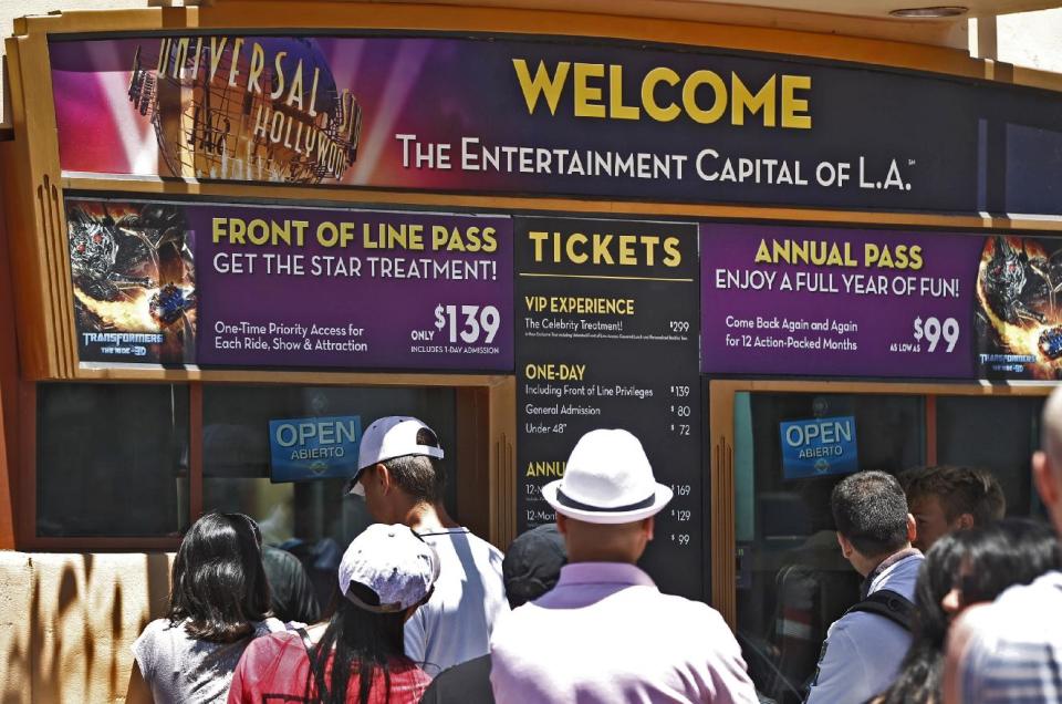 This photo taken Wednesday, June 5, 2013, shows tourists purchasing tickets at Universal Studios Hollywood in Los Angeles. Many theme parks now have VIP tours with perks usually reserved for celebrities _ private tour guides, no waits for the biggest attractions, reserved seating at shows and parades along with behind-the-scenes peaks at places normally off limits. (AP Photo/Damian Dovarganes)