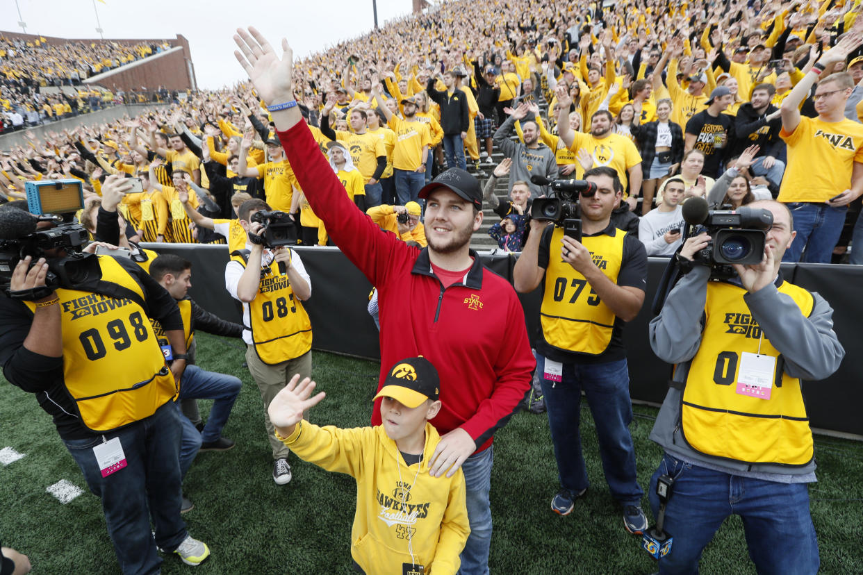 Carson King, of Altoona, Iowa, center, waves to patients in the University of Iowa Stead Family Children's Hospital at the end of the first quarter of an NCAA college football game between Iowa and Middle Tennessee, Saturday, Sept. 28, 2019, in Iowa City, Iowa. King plans to donate more than $1 million to charity after his decision to display a hand-written sign before the Sept. 14 Iowa State-Iowa football game seeking money for beer prompted an overwhelming number of donations. (AP Photo/Charlie Neibergall)