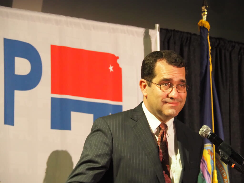 Derek Schmidt appears on stage in front of a GOP banner on election night