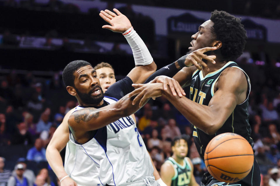 Dallas Mavericks guard Kyrie Irving, left, and Charlotte Hornets center Mark Williams battle for the ball during the first half of an NBA basketball game in Charlotte, N.C., Sunday, March 26, 2023. (AP Photo/Nell Redmond)