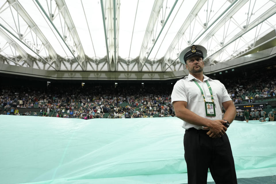 A member of security stands beneath the closed roof on Centre Court as rain stopped play on day four of the Wimbledon tennis championships in London, Thursday, June 30, 2022. (AP Photo/Kirsty Wigglesworth)