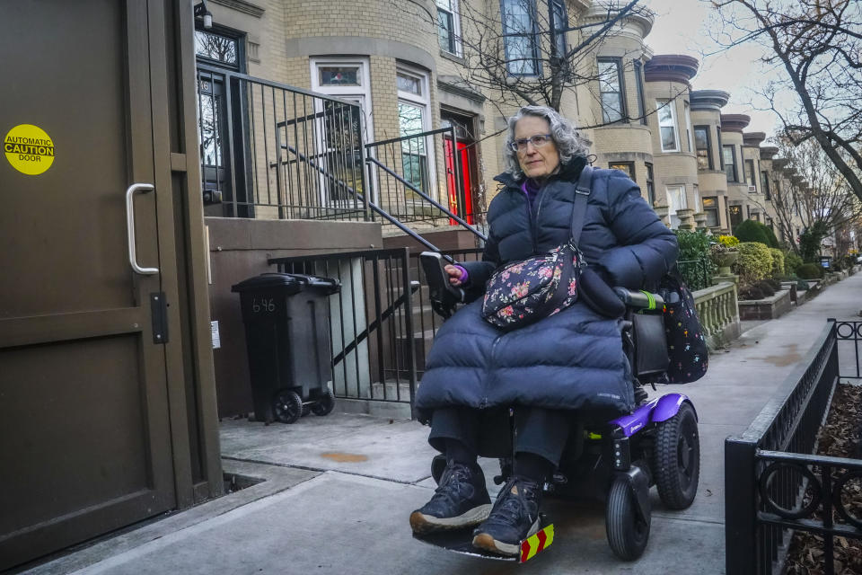 Jean Ryan, president of the advocacy group Disabled In Action, rides her motorized wheelchair to meet a car service for disabled individuals, which will transport her from home in Brooklyn to Manhattan, Wednesday, Feb. 7, 2024, in New York. The Big Apple is close to implementing a plan that would use license-plate readers to turn all of Manhattan south of Central Park into one giant toll zone. (AP Photo/Bebeto Matthews)