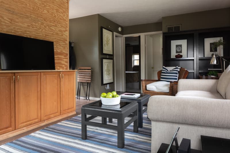 Gray living room with black shelf wicker chair and grey couch.