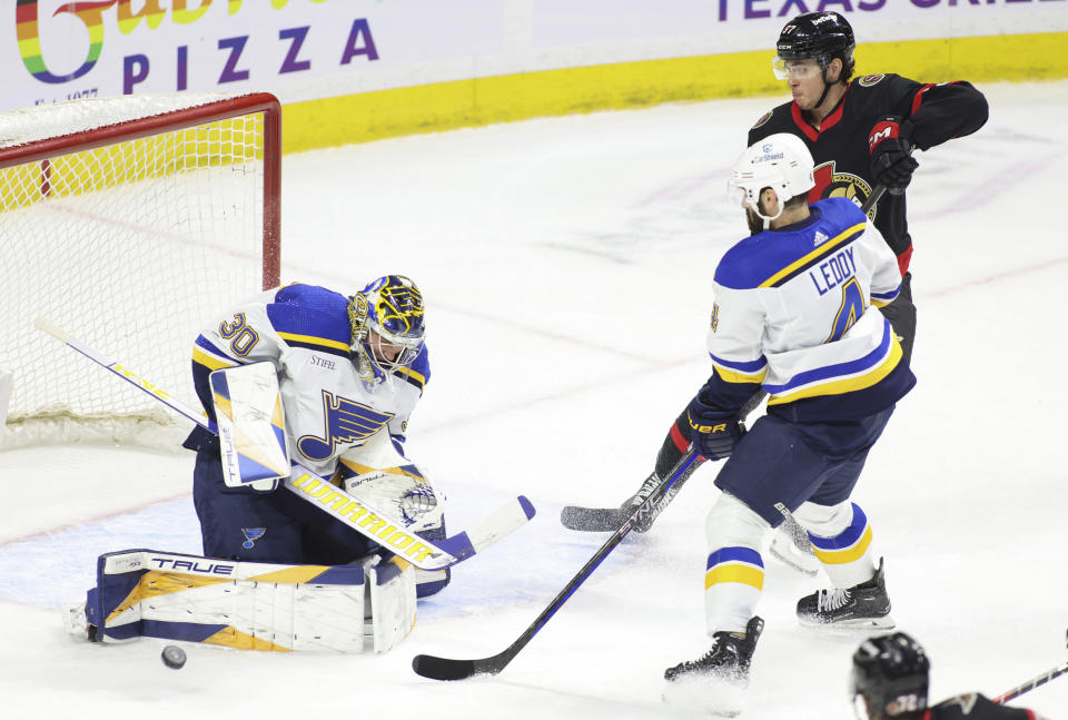 St. Louis Blues goaltender Joel Hofer (30) makes a save as Ottawa Senators' Shane Pinto (57) as Blues' Nick Leddy (4) look on during the first period of an NHL hockey game in Ottawa, Ontario, on Thursday, March 21, 2024. (Patrick Doyle/The Canadian Press via AP)
