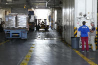 Members staff of U.S Aid, stand at right as a worker unloads Gaza aid from a truck inside a U.S ship at the port of Larnaca, Cyprus, Wednesday, June 26, 2024. An official with the U.S. humanitarian assistance agency USAID says thousands of tons of food, medicines and other aid piled up on a Gaza beach isn't reaching those in need because of a dire security situation on the ground where truck drivers are either getting caught in the crossfire or have their cargo seized by "gang-like" groups. (AP Photo/Petros Karadjias)