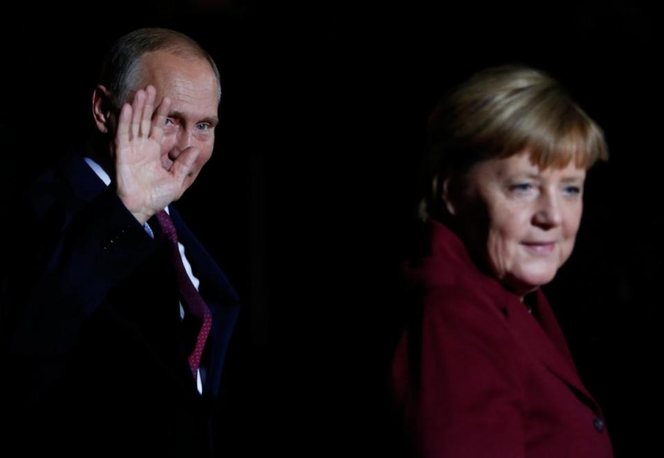 Russian President Vladimir Putin waves next to German Chancellor Angela Merkel as he arrives for talks on a stalled peace plan for eastern Ukraine at the chancellery in Berlin, Germany, October 19, 2016. REUTERS/Hannibal Hanschke
