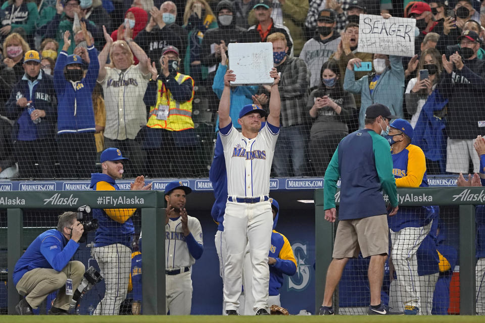 Seattle Mariners third baseman Kyle Seager holds up third base after it was given to him when he was subbed out of a baseball game against the Los Angeles Angels during the ninth inning, Sunday, Oct. 3, 2021, in Seattle. (AP Photo/Ted S. Warren)