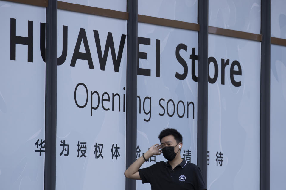 A man wearing a mask to curb the spread of the coronavirus walks past a soon to open Huawei store in Beijing on Wednesday, July 15, 2020. China's government accused Britain on Wednesday of colluding with Washington to hurt Chinese companies after tech giant Huawei was blocked from working on a next-generation mobile phone network. (AP Photo/Ng Han Guan)