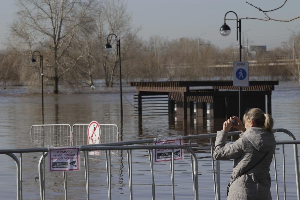 A woman takes a photo of a flooded area next to Ural river in Orenburg, Russia, on Thursday, April 11, 2024. Russian officials are scrambling to help homeowners displaced by floods, as water levels have risen in the Ural River. The river's water level in the city of Orenburg was above 10 meters (33 feet) Wednesday, state news agency Ria Novosti reported, citing the regional governor. (AP Photo)