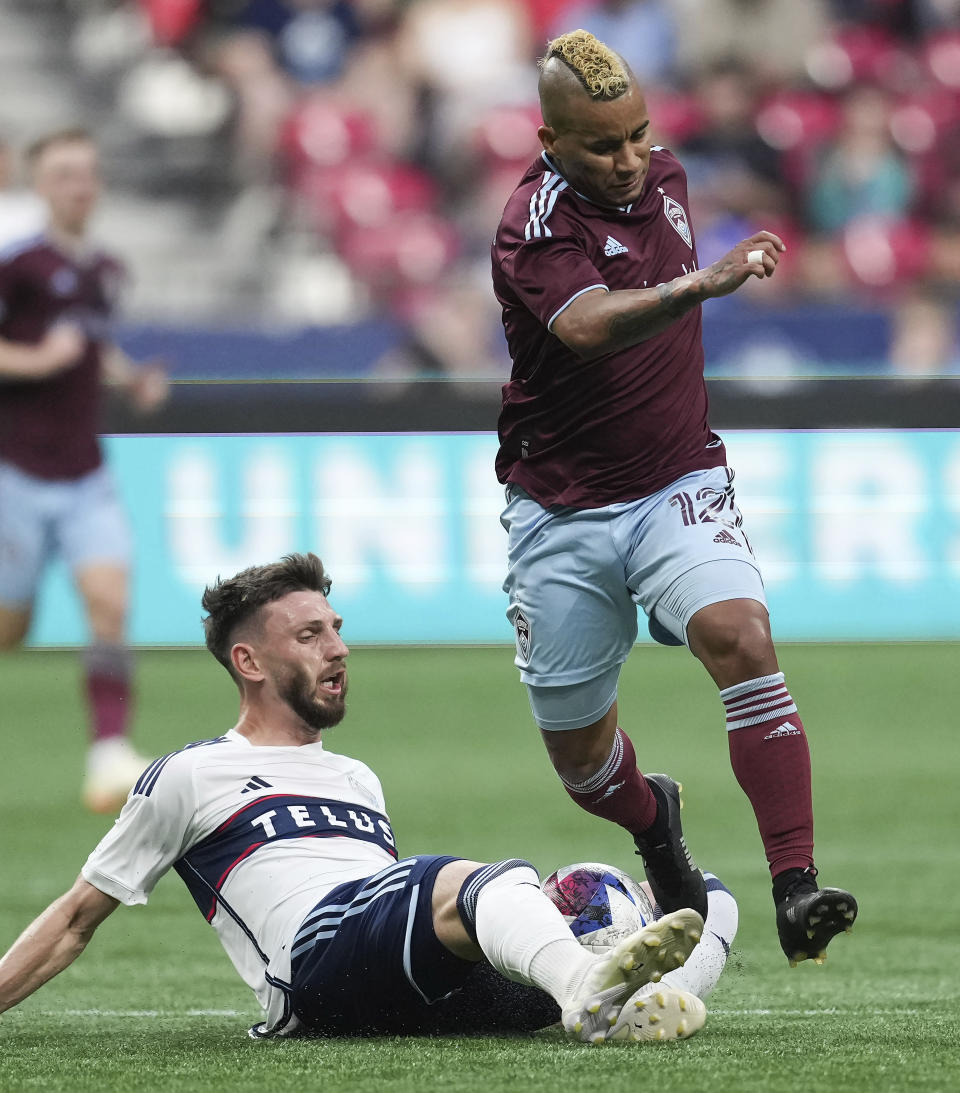 Vancouver Whitecaps' Tristan Blackmon, left, dives to take the ball away from Colorado Rapids' Michael Barrios during the first half of an MLS soccer match Saturday, April 29, 2023, in Vancouver, British Columbia. (Darryl Dyck/The Canadian Press via AP)