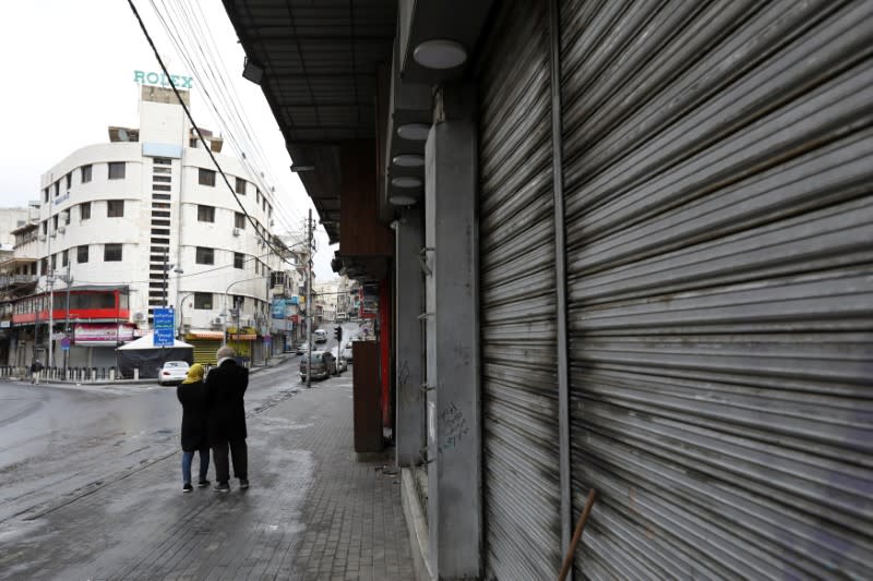 FILE PHOTO: People walk next to closed shops in Amman
