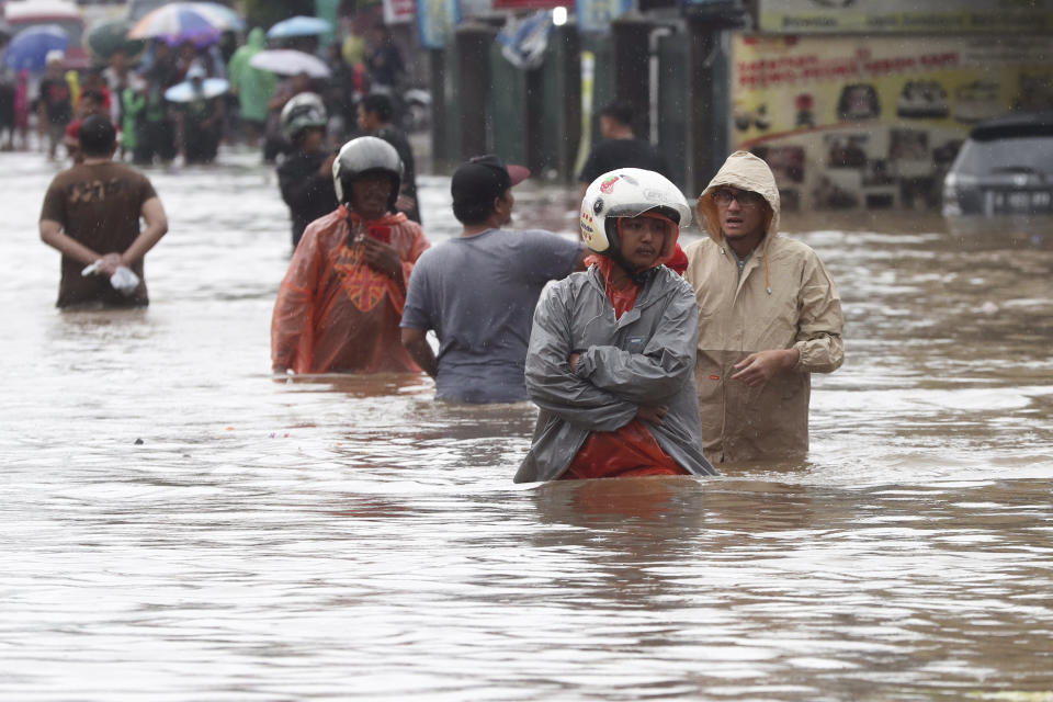 Indonesian people wade through floodwaters at Jatibening on the outskirt of Jakarta, Indonesia, Wednesday, Jan. 1, 2020. Severe flooding hit Indonesia's capital just after residents celebrating New Year's Eve, forcing a closure of an airport and thousands of inhabitants to flee their flooded homes. (AP Photo/Achmad Ibrahim)