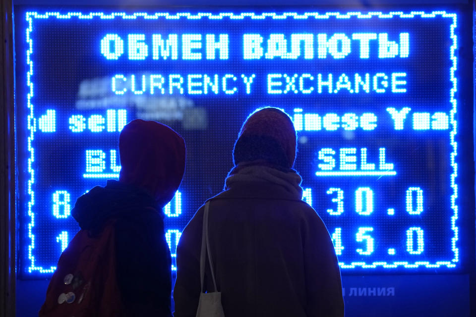 FILE - Women look at a screen displaying exchange rate at a currency exchange office in St. Petersburg, Russia, Tuesday, March 1, 2022. In the days since the West imposed sanctions on Russia over its invasion of Ukraine, ordinary Russians are feeling the painful effects — from payment systems that won't operate and problems withdrawing cash to not being able to purchase certain items. (AP Photo/Dmitri Lovetsky, File)