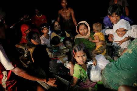 A man lifts an elderly woman from the boat as hundreds of Rohingya refugees arrive under the cover of darkness from Myanmar to the shore of Shah Porir Dwip, in Teknaf, near Cox's Bazar in Bangladesh. REUTERS/Damir Sagolj