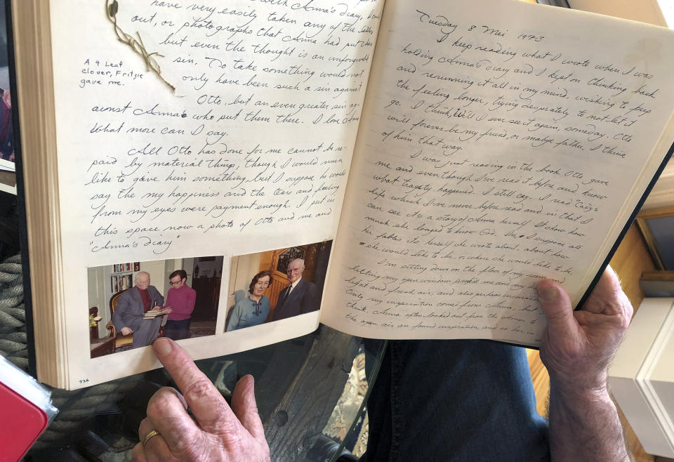 In this June 7, 2019 photo, Ryan Cooper displays pages from a 1973 portion of a diary at his home in Yarmouth, Mass., which he wrote when he visited Otto Frank, the father of the famed Holocaust victim and diarist Anne Frank. Cooper is pointing to a photo of him with Otto Frank while holding Anne's original diary. Cooper has donated a trove of letters and mementos he received from Otto Frank to the U.S. Holocaust Memorial Museum ahead of the 90th anniversary of Anne Frank's birthday. (AP Photo/Philip Marcelo)