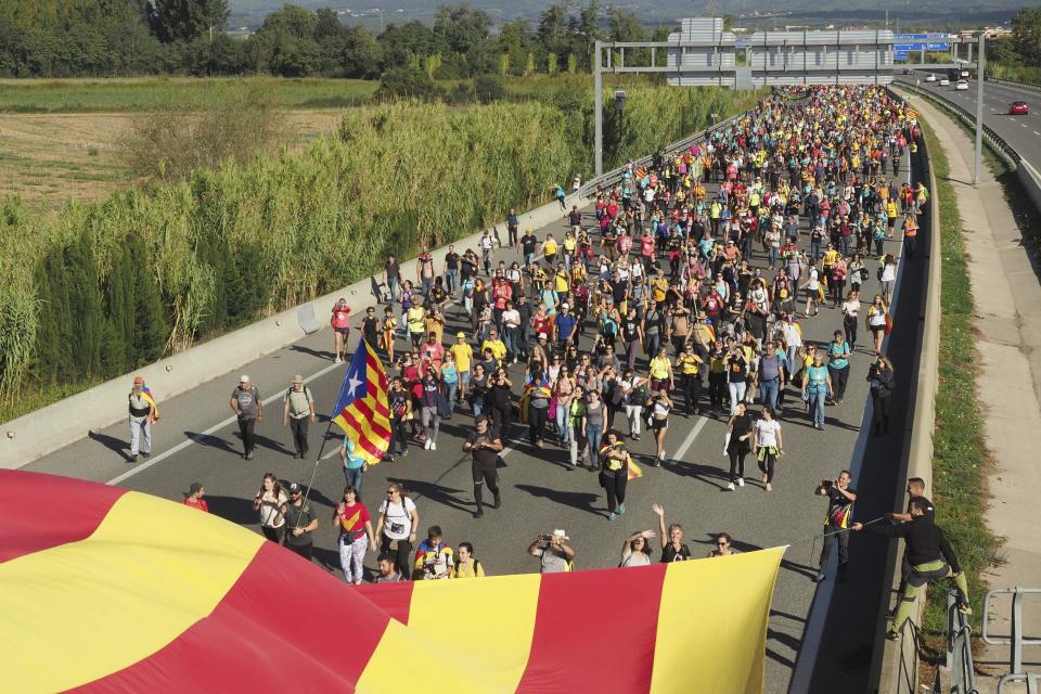 Demonstrators walk along a highway in Girona, Spain, Wednesday, Oct. 16, 2019. Thousands of people have joined five large protest marches across Catalonia that are set to converge on Barcelona, as the restive region reels from two straight days of violent clashes between police and protesters. The marches set off from several Catalan towns and aimed to reach the Catalan capital by Friday. (AP Photo/Mar Grau)