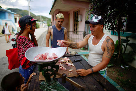 Self-employed Bilmar Alvarez (R), 32, sells meat on the street in El Cobre, Cuba, April 2, 2018. Picture taken April 2, 2018. REUTERS/Alexandre Meneghini
