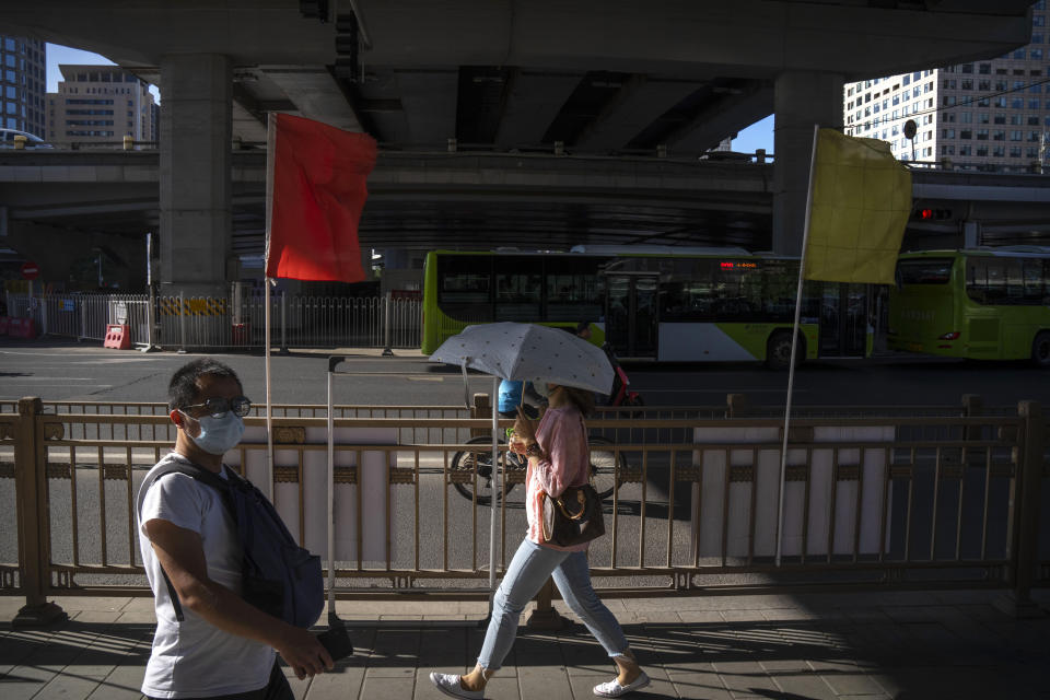 Commuters wearing face masks walk through a highway underpass in the central business district in Beijing, Thursday, Sept. 1, 2022. (AP Photo/Mark Schiefelbein)