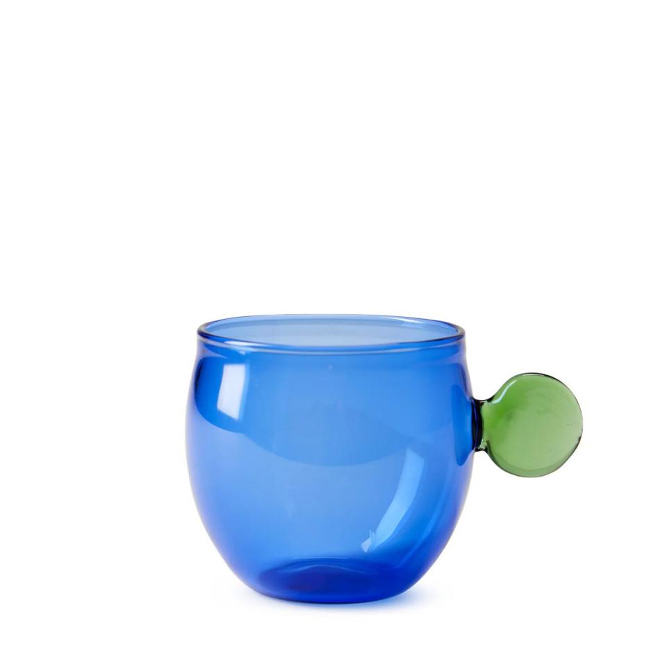 a blue glass cup with a green handle