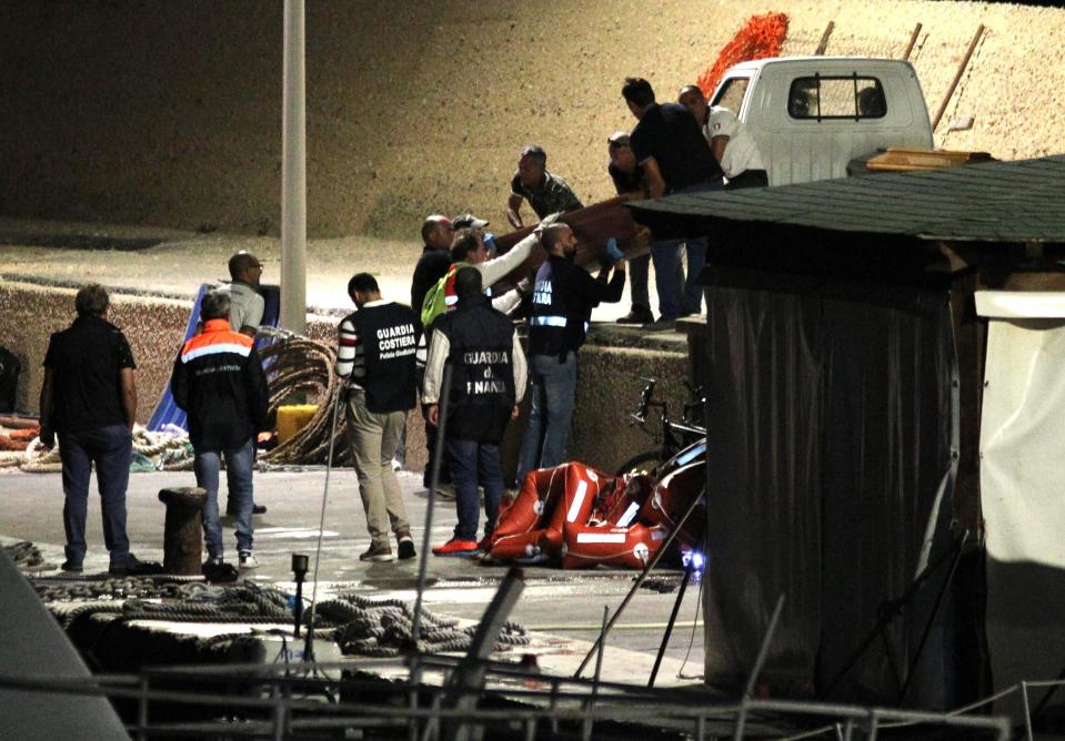 Italian Coast Guard officers carry a coffin with the body of a migrant, in the Lampedusa harbor, Italy, early Monday, Oct. 7, 2019. The Italian Coast Guard says at least nine people have died when a migrant boat capsized near the island of Lampedusa as they were about to be rescued. Twenty-two people were saved. (Pasquale Claudio Montana Lampo/ANSA via AP)