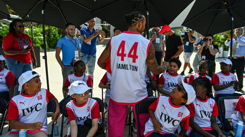 At an event leading up to the 2023 Miami Grand Prix, Lewis Hamilton greets a group of local kids in attendance.